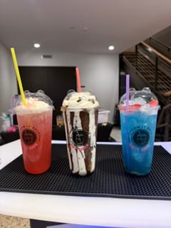 Three dirty sodas lined up in branded cups